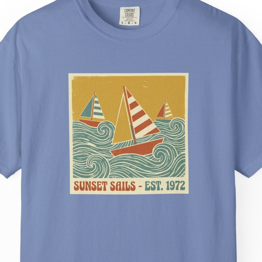 Blue t-shirt with a sailboat graphic and 'Sunset Sails' text on a white background