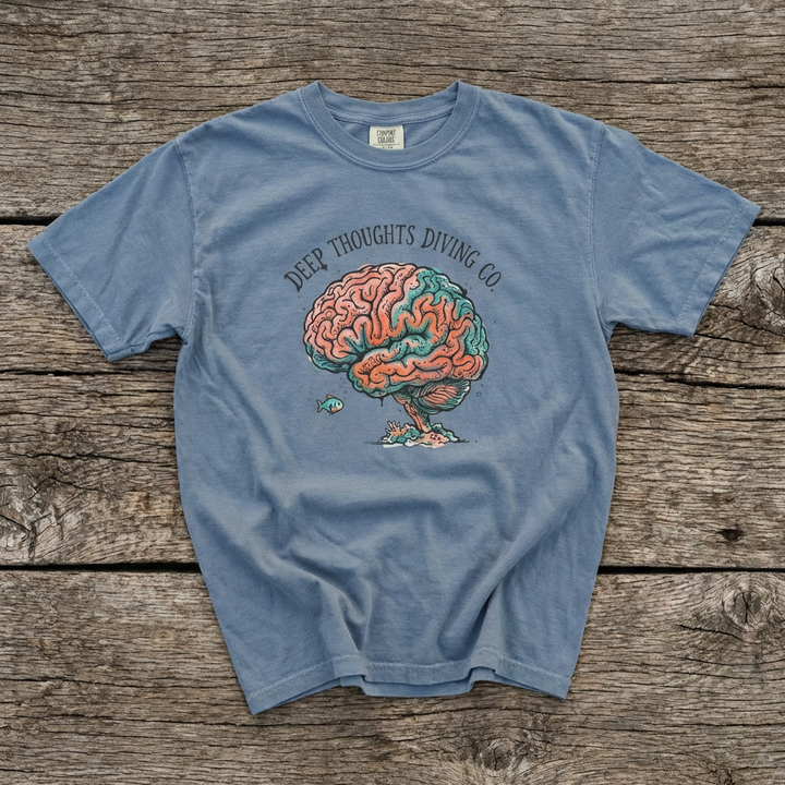 Blue t-shirt with a brain graphic and text on a wooden surface