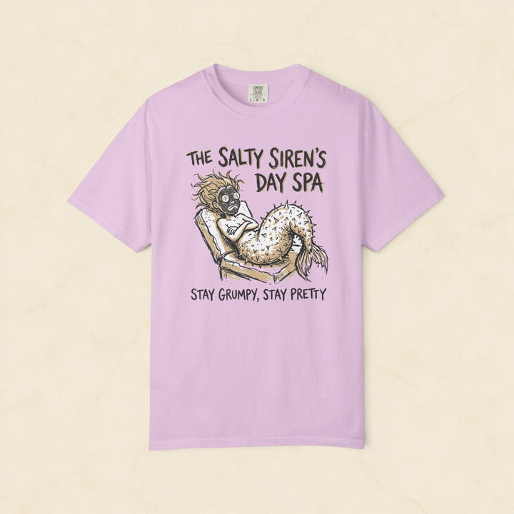 Pink t-shirt with a mermaid graphic and text on a white background