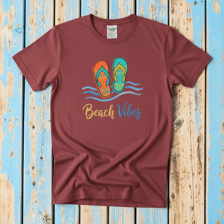 Flat lay - crimson red Beach Vibes tee with Comfort Colors label on weathered driftwood planks