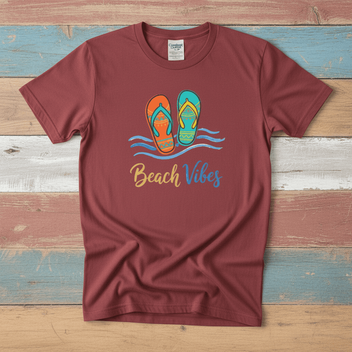 Flat lay - crimson red Beach Vibes tee with Comfort Colors label on weathered driftwood planks