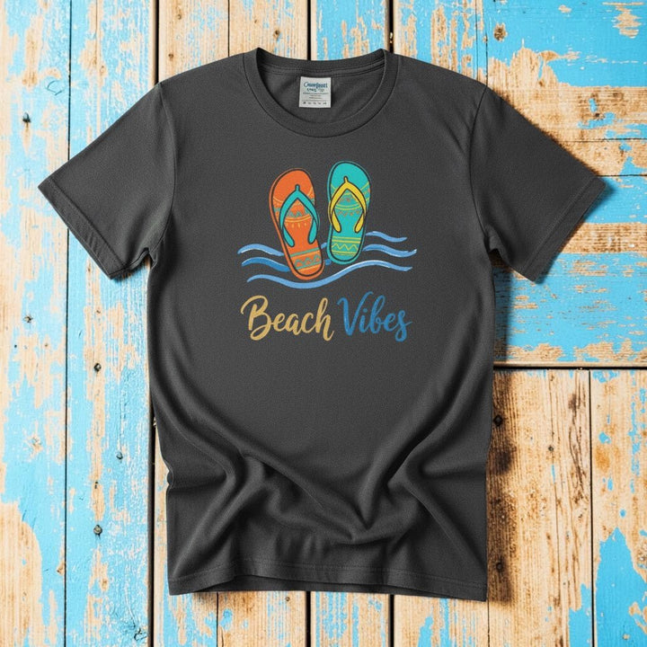 Flat lay - charcoal Beach Vibes tee with Comfort Colors label on weathered driftwood planks