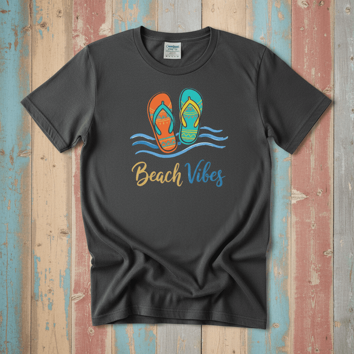 Flat lay - charcoal Beach Vibes tee with Comfort Colors label on weathered driftwood planks