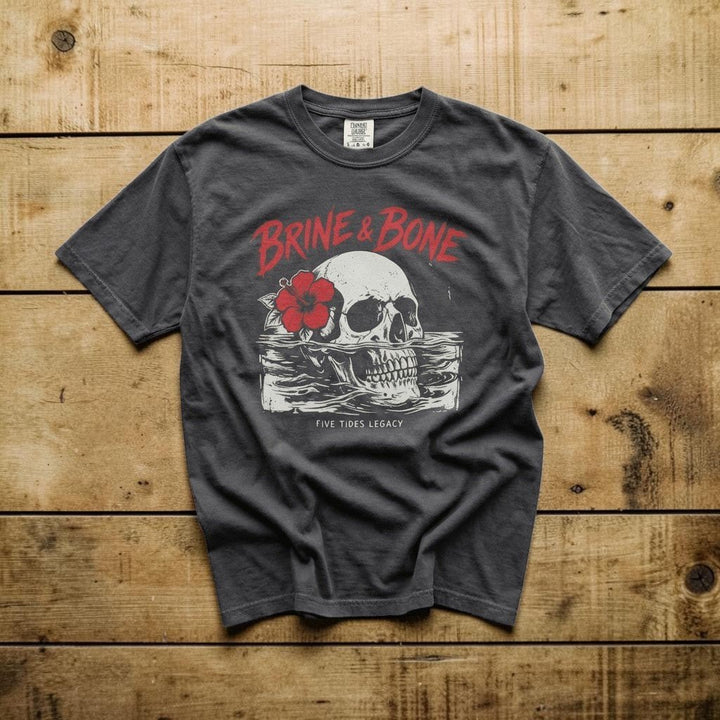Gray t-shirt with skull and flower graphic on a concrete surface