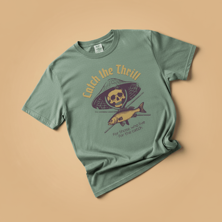 Catch the Thrill Tee in Sage Green — front graphic, warm sand studio background