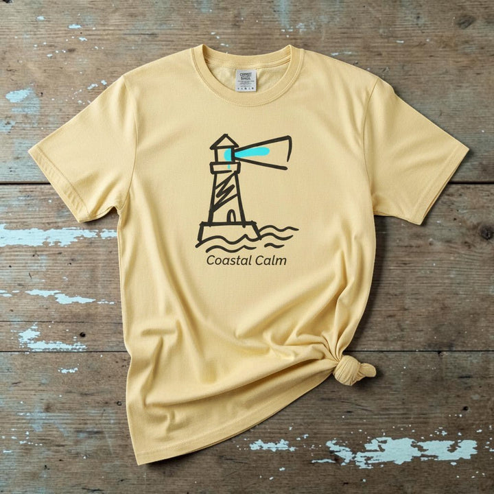 Coastal Calm Lighthouse banana garment-dyed tee on faded driftwood planks