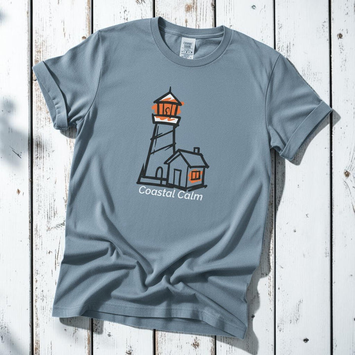 Coastal Calm Orange Lookout Lighthouse blue jean garment-dyed tee on faded driftwood planks