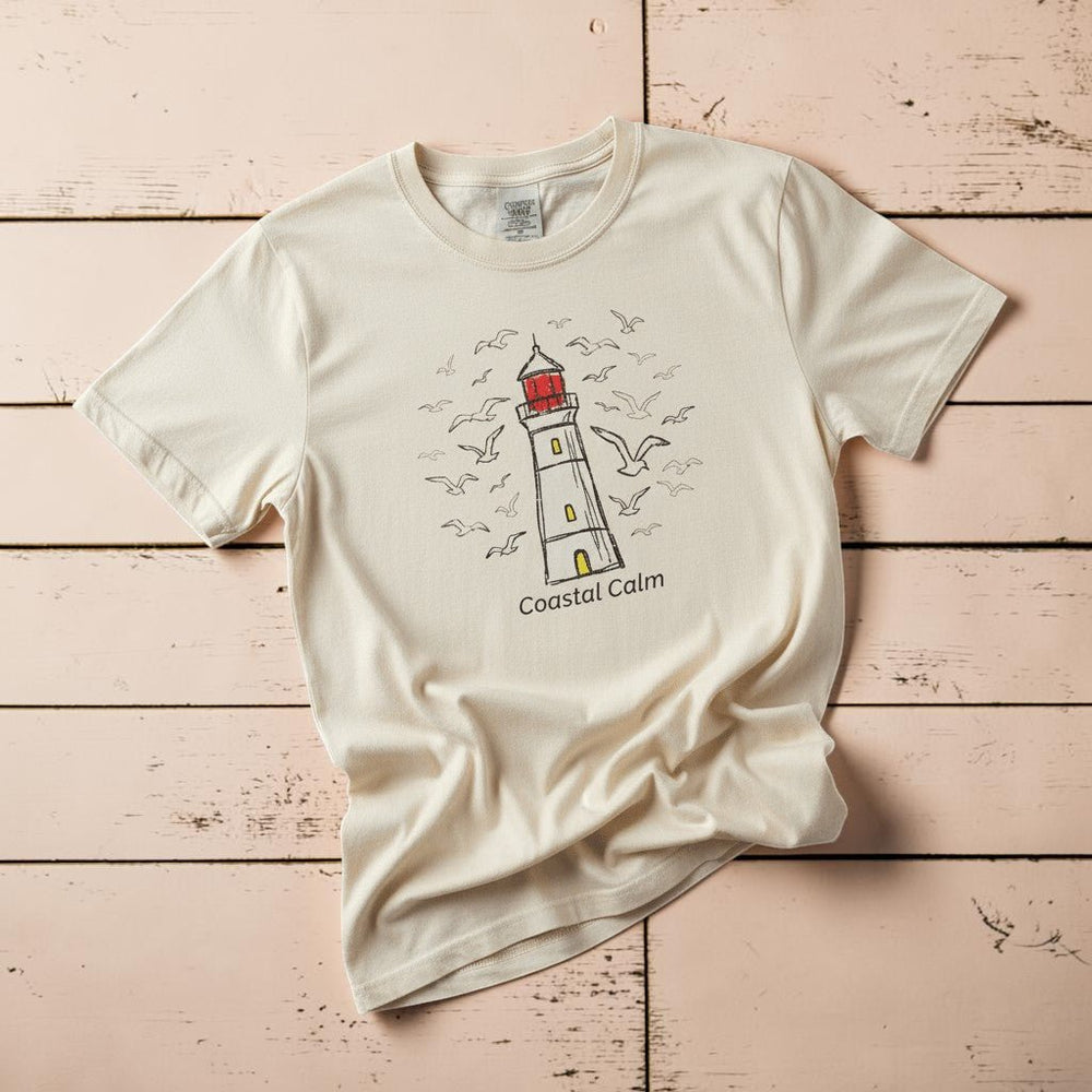Coastal Calm Seabirds Lighthouse ivory garment-dyed tee on faded driftwood planks