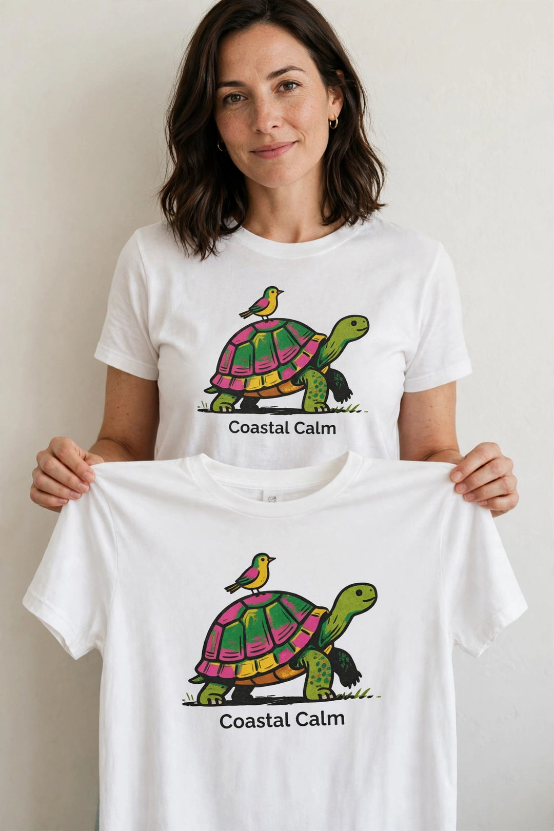 Woman wearing the Coastal Calm Turtle Buddies Tee in White, holding up the front print.