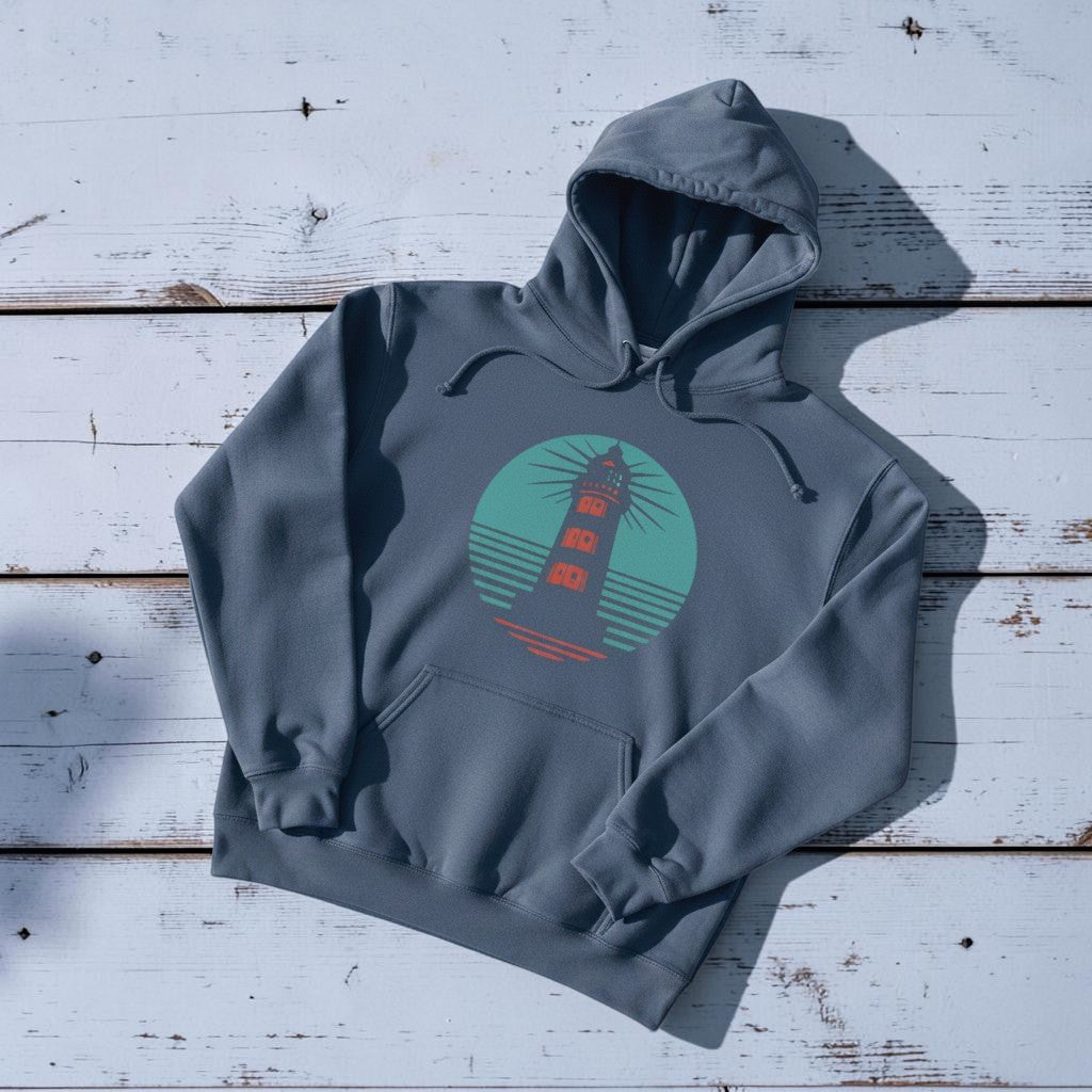 Coastal Lighthouse Hoodie in Denim — front graphic, warm sand studio background