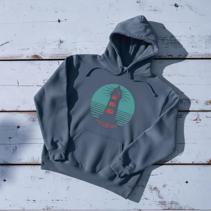 Coastal Lighthouse Hoodie in Denim — front graphic, warm sand studio background