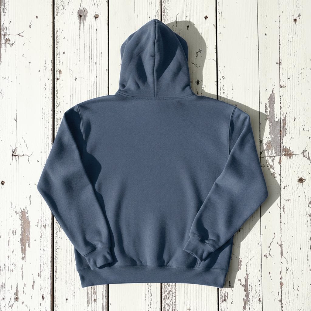 Coastal Lighthouse Hoodie in Denim — plain back, warm sand studio background