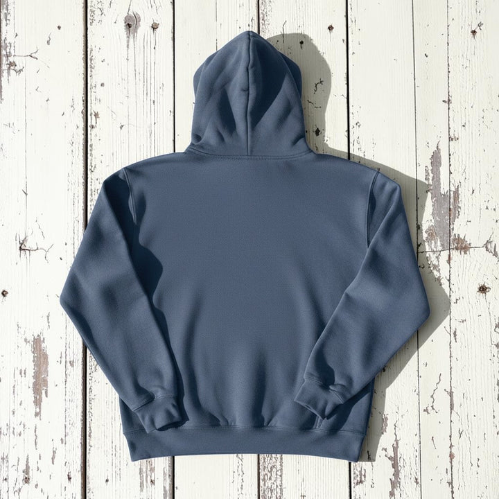Coastal Lighthouse Hoodie in Denim — plain back, warm sand studio background
