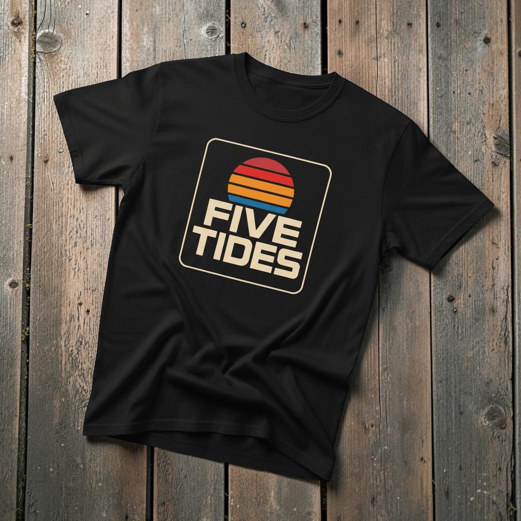 Coastal Retro Sunset black garment-dyed tee on faded driftwood planks