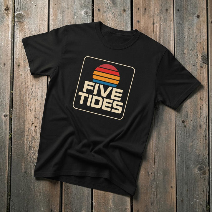 Coastal Retro Sunset black garment-dyed tee on faded driftwood planks