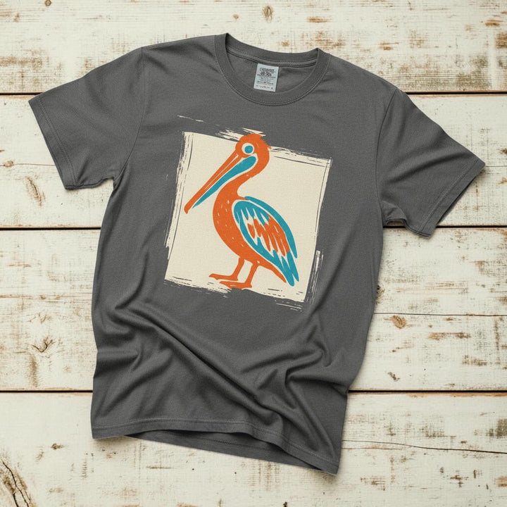 Colorful Beach Pelican pepper garment-dyed tee on faded driftwood planks
