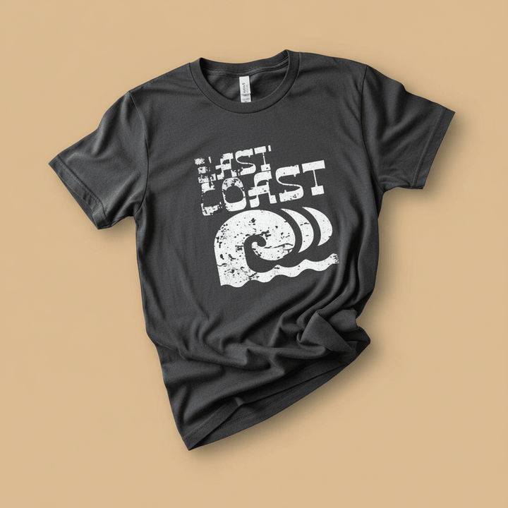 East Coast Tee in Pepper/Charcoal — front graphic, warm sand studio background