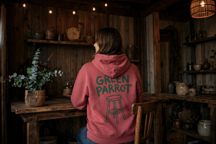 Green Parrot Bar Stool Hoodie — in the Five Tides room, female back