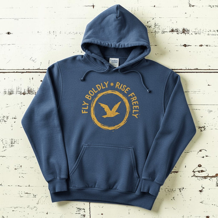 Denim blue Fly Boldly Rise Freely hoodie flat lay on weathered driftwood planks