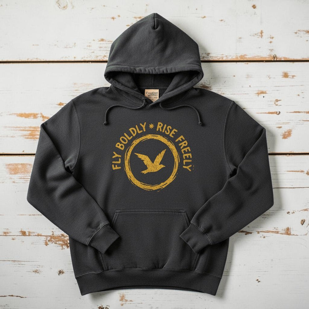 Charcoal Fly Boldly Rise Freely hoodie flat lay on weathered driftwood planks