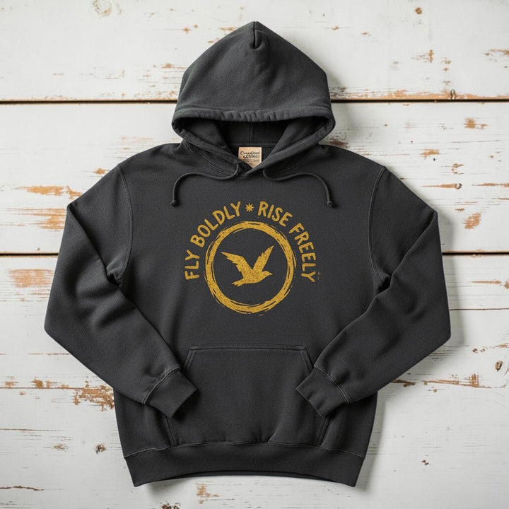 Charcoal Fly Boldly Rise Freely hoodie flat lay on weathered driftwood planks