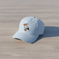 Pelican Beach light blue dad cap on light cracked cement with wet marks