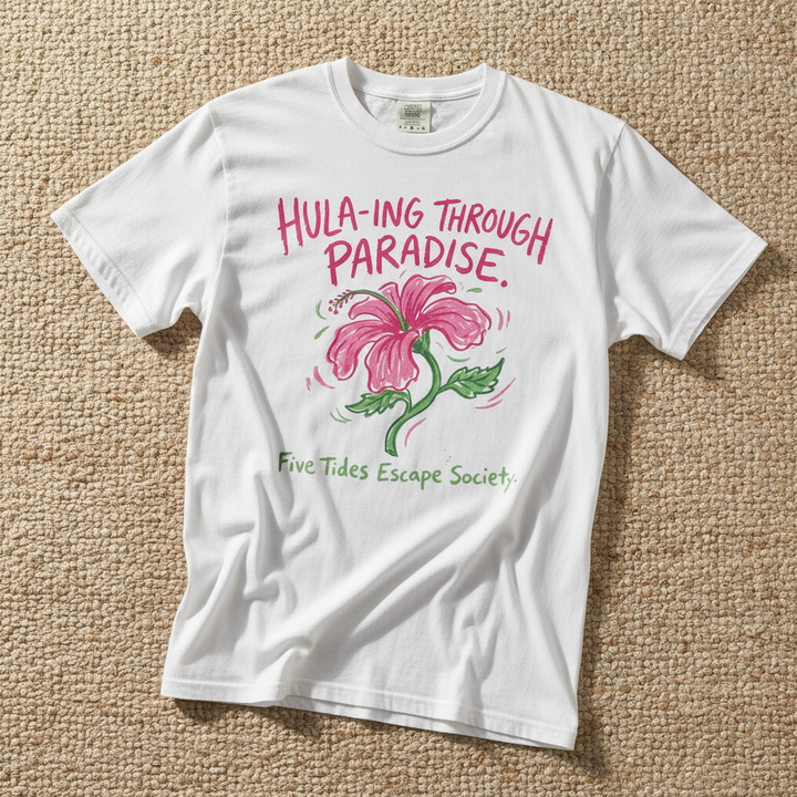 Hula-ing Through Paradise hibiscus floral graphic t-shirt in White casually tossed on a light sand-colored woven rug, tropical lifestyle product photo