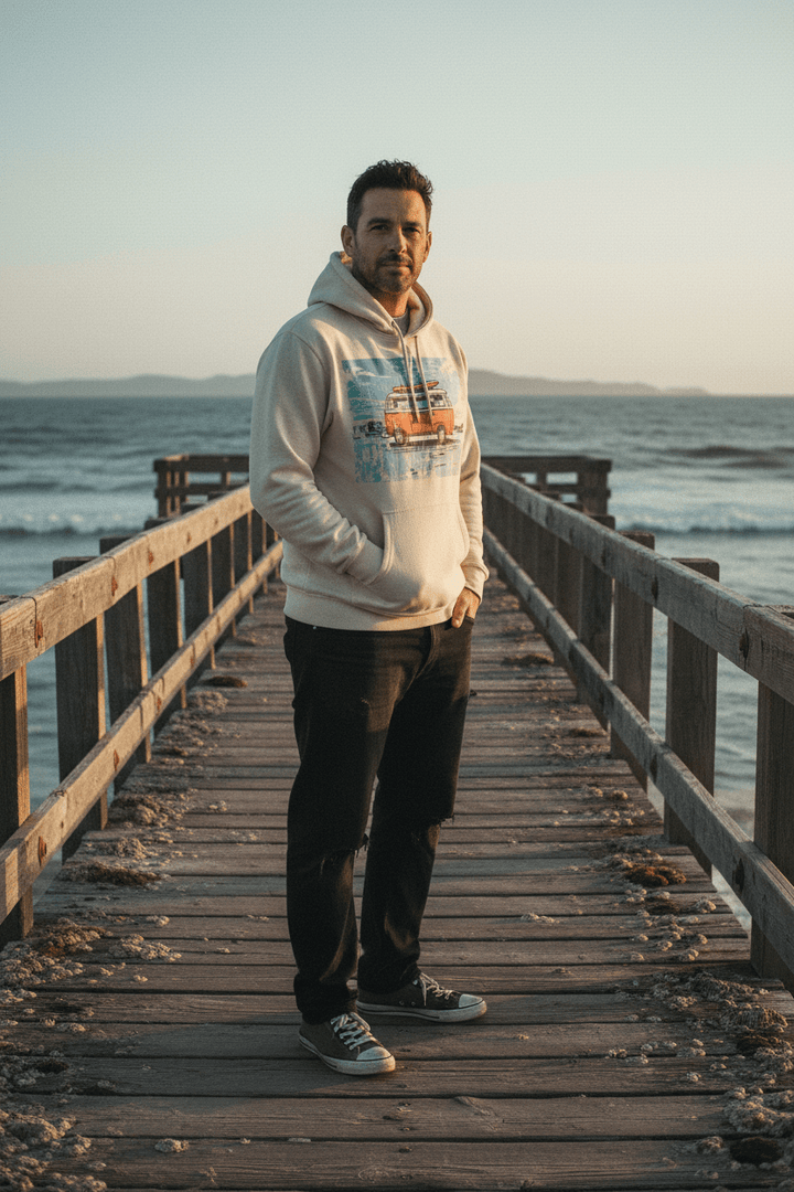 Man in his late 30s wearing Retro Surf Van sandshell hoodie on weathered beach dock