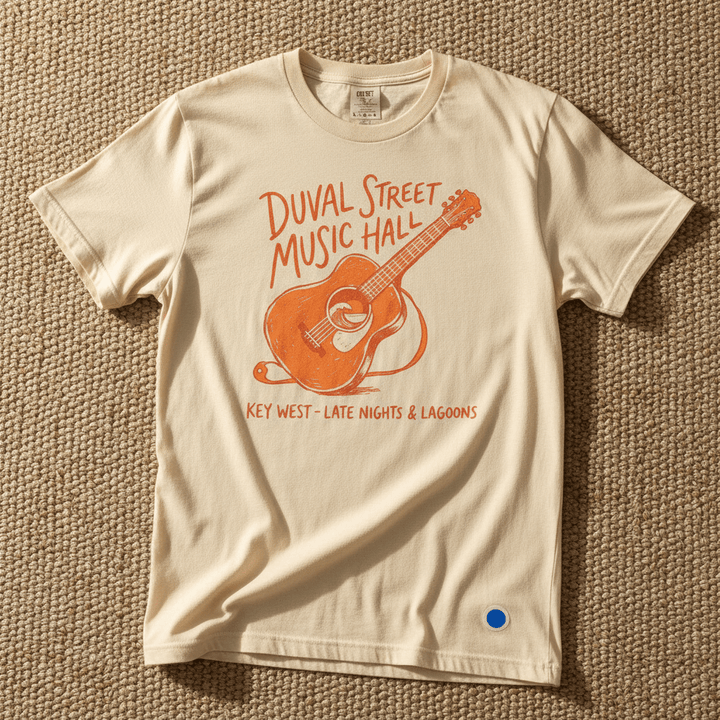 Duval Street Music Hall guitar graphic t-shirt in Ivory cream casually tossed on a light sand-colored woven rug, Key West lifestyle product photo