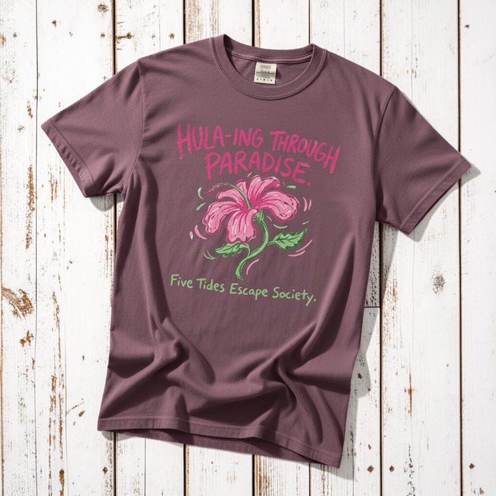 Hula-ing Through Paradise hibiscus floral graphic t-shirt in Berry deep pink casually tossed on a light sand-colored woven rug, tropical lifestyle product photo