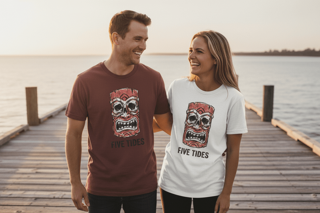 Couple wearing maroon and white Five Tides tiki skull t-shirts on sun-bleached boat dock