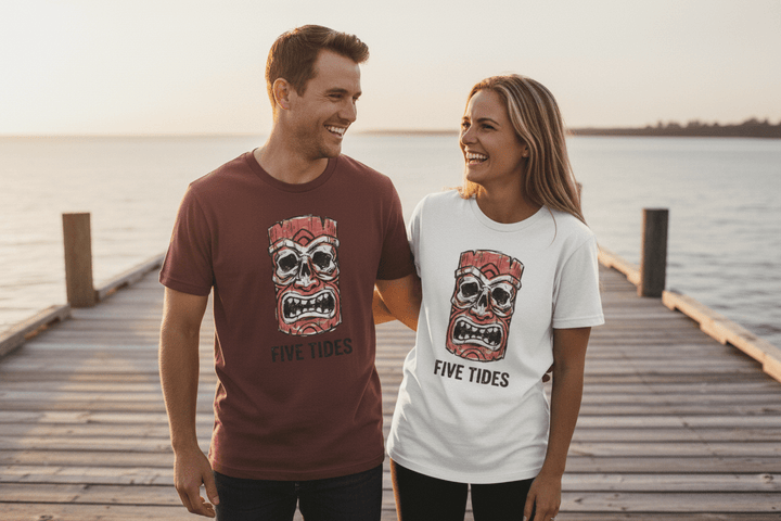 Couple wearing maroon and white Five Tides tiki skull t-shirts on sun-bleached boat dock