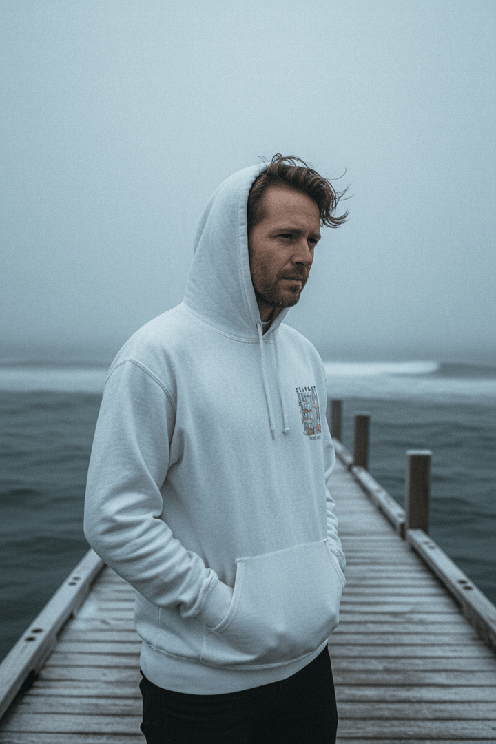 Male model wearing white Seaport Fish Market Boston hoodie on frost-dusted bleached wood boat dock