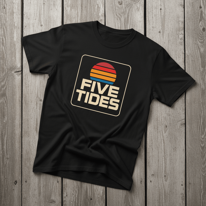 Coastal Retro Sunset black garment-dyed tee on faded driftwood planks