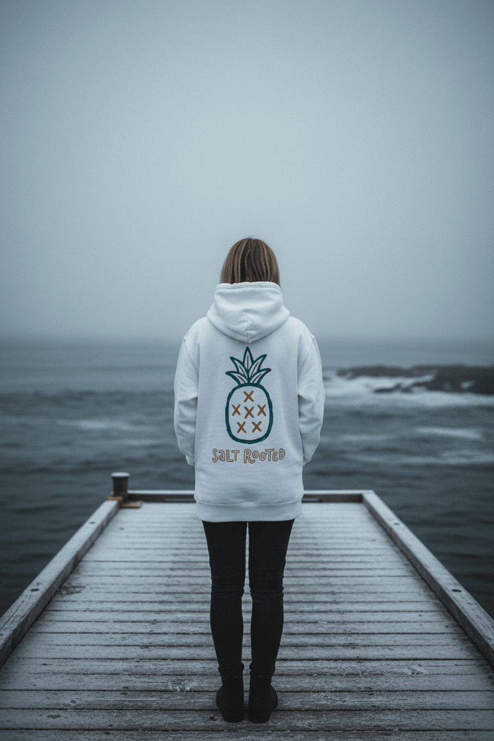 Female model showing back of white Salt Rooted pineapple hoodie on frost-dusted bleached wood boat dock