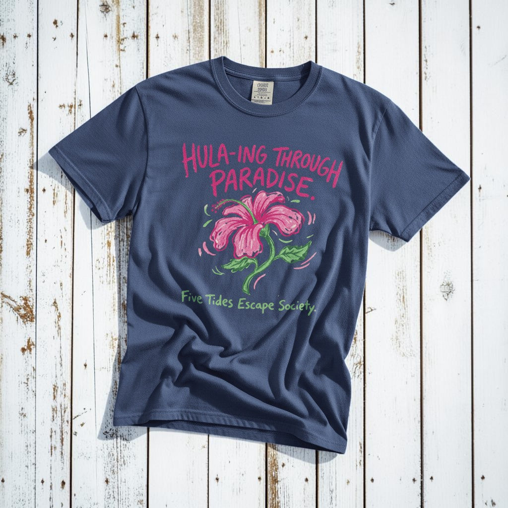 Hula-ing Through Paradise hibiscus floral graphic t-shirt in China Blue casually tossed on a light sand-colored woven rug, tropical lifestyle product photo