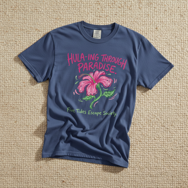 Hula-ing Through Paradise hibiscus floral graphic t-shirt in China Blue casually tossed on a light sand-colored woven rug, tropical lifestyle product photo