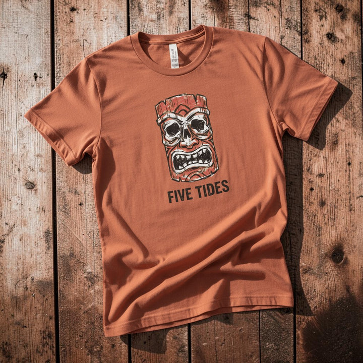 Red Tiki Skull FIVE TIDES surf graphic t-shirt in Terracotta casually tossed on a light sand-colored woven rug, coastal lifestyle product photo