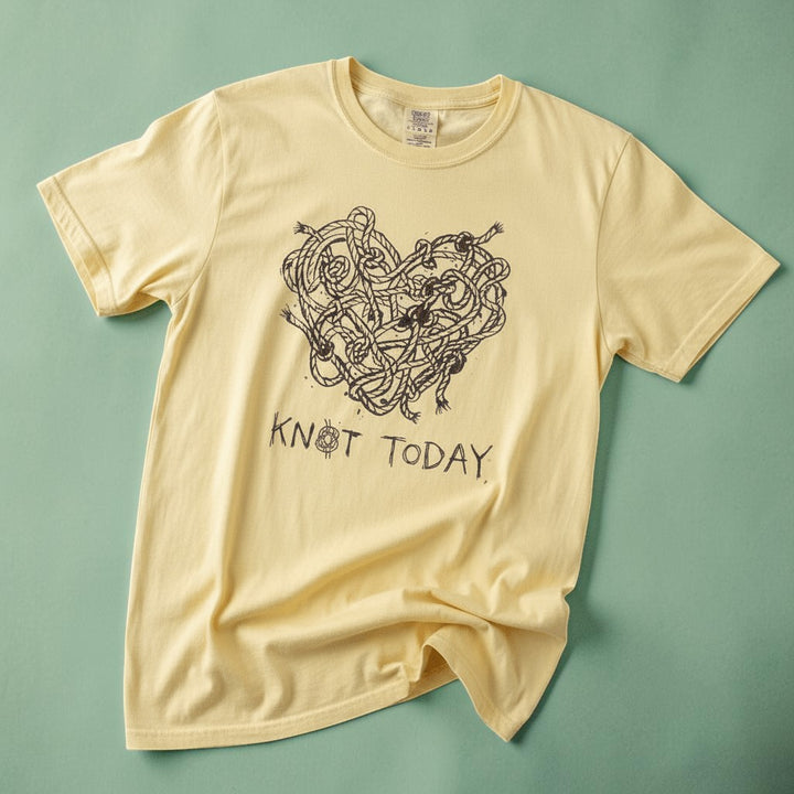 Knot Today banana garment-dyed tee on faded driftwood planks