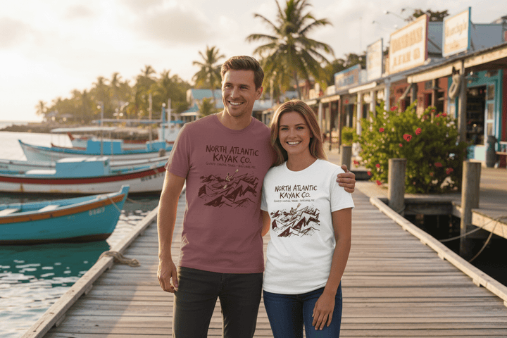 Couple wearing mauve and white North Atlantic Kayak Co. t-shirts on tropical island beach town boat dock