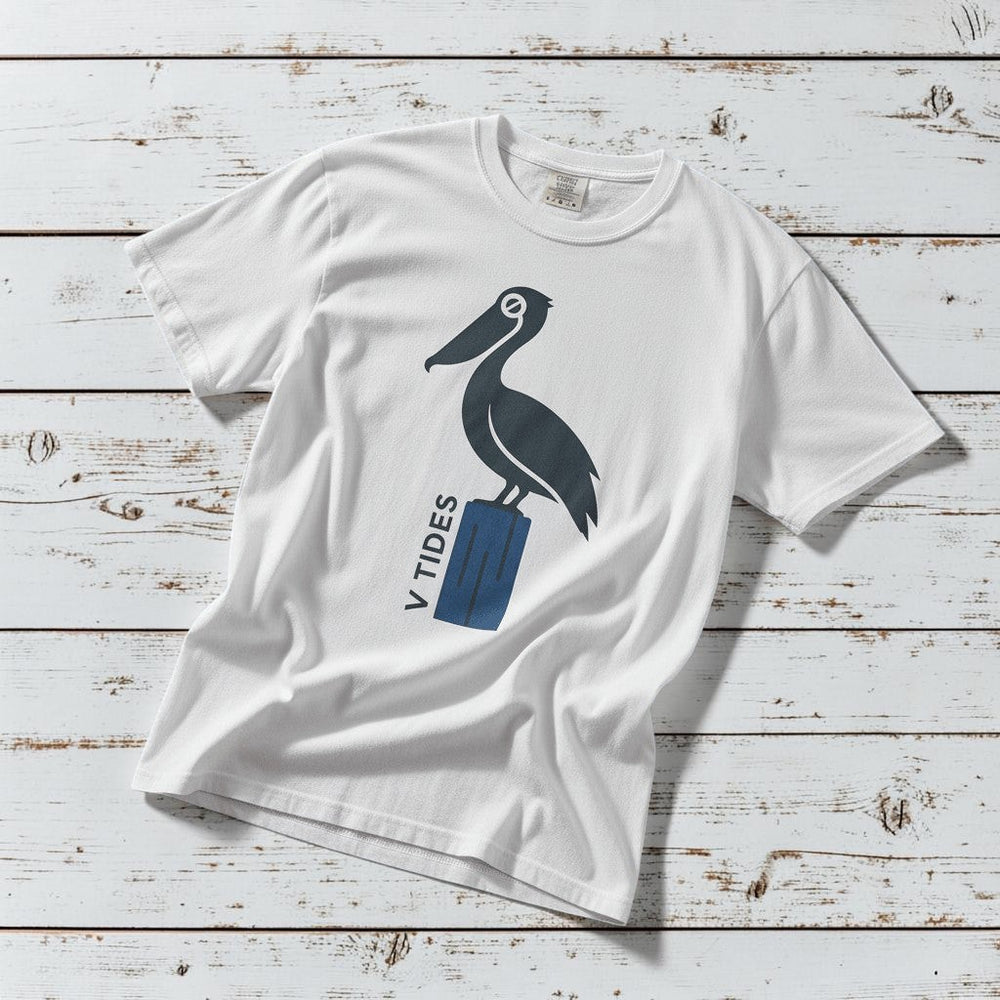 Pelican Dock V Tides coastal graphic t-shirt in White casually tossed on a light sand-colored woven rug, coastal lifestyle product photo