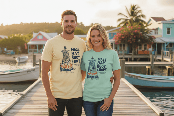 Couple wearing banana and mint Mass Bay Buoy &amp; Rope t-shirts on tropical island beach town boat dock