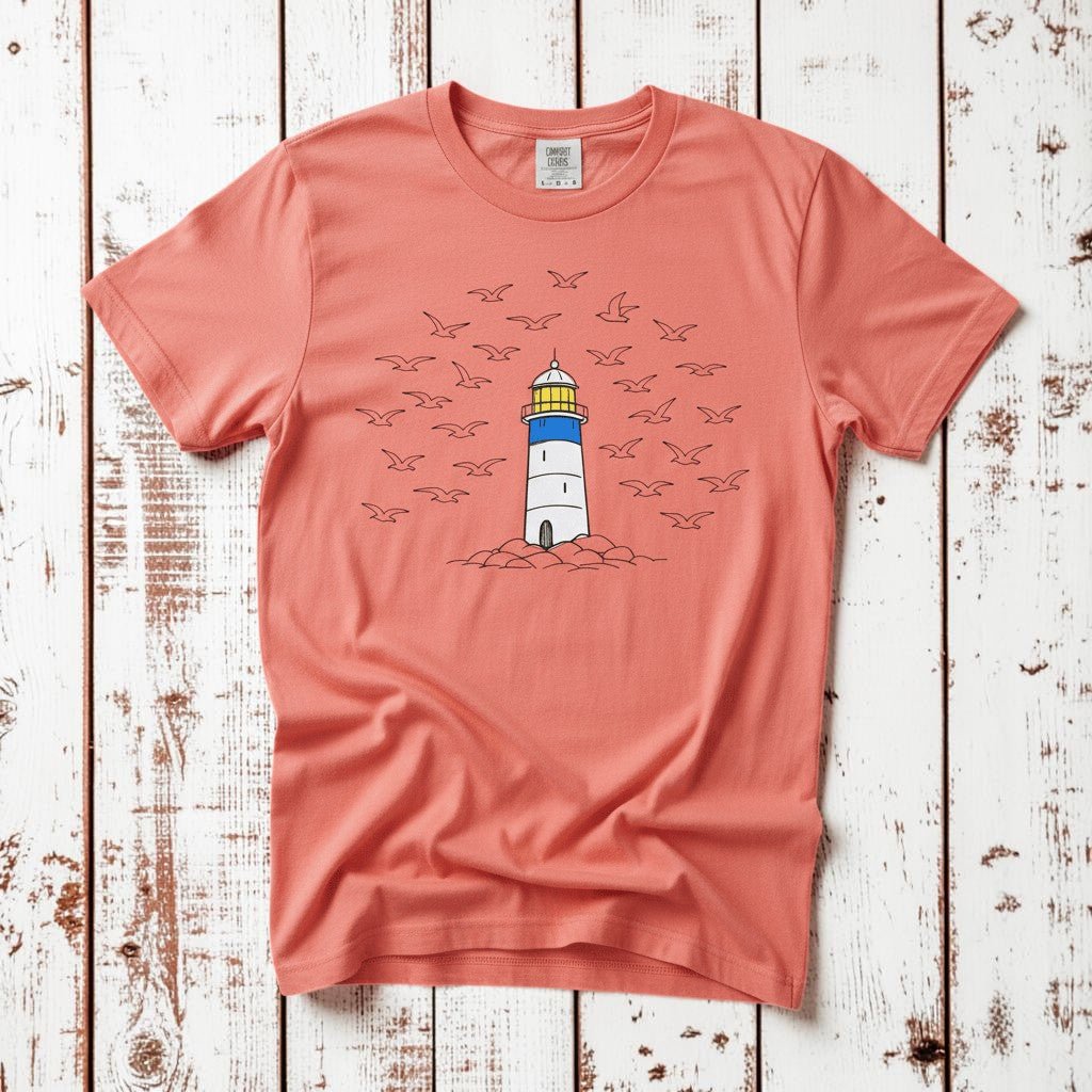 Lighthouse Coastal bright salmon garment-dyed tee on faded driftwood planks