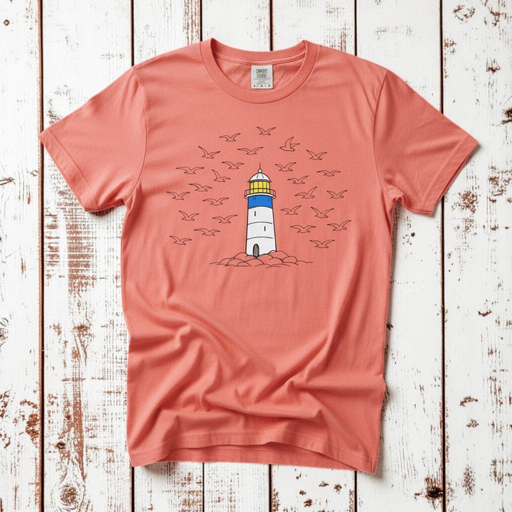 Lighthouse Coastal bright salmon garment-dyed tee on faded driftwood planks