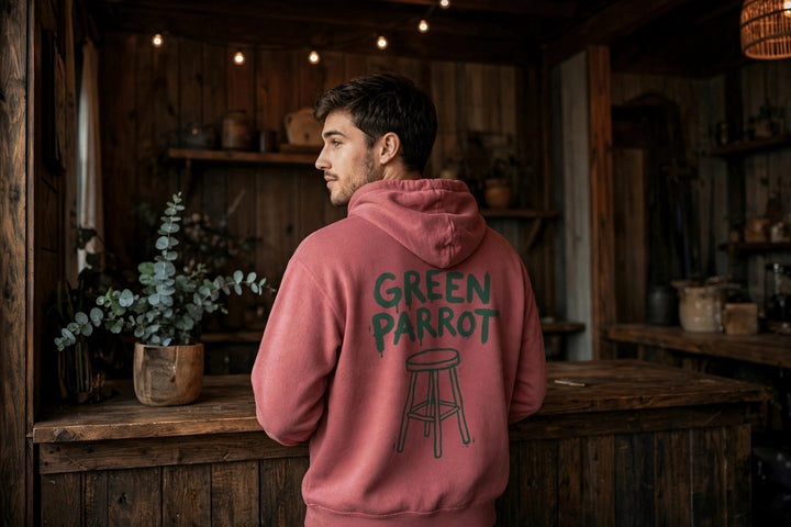 Green Parrot Bar Stool Hoodie — in the Five Tides room, male back