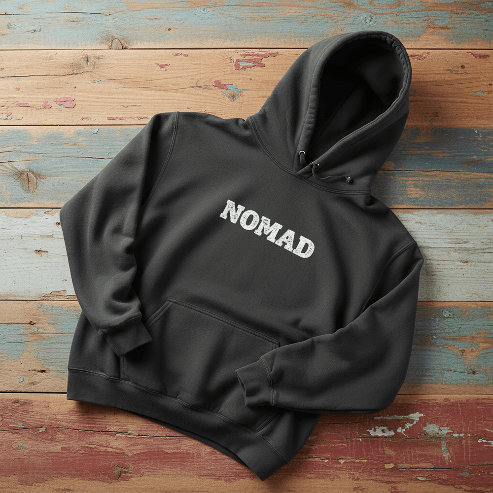 Nomad Garment-Dyed Hoodie in Pepper — front NOMAD chest graphic on driftwood