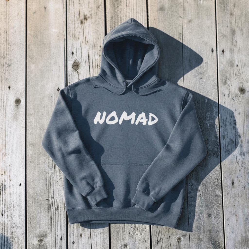 NOMAD Hoodie in Blue — front graphic, warm sand studio background
