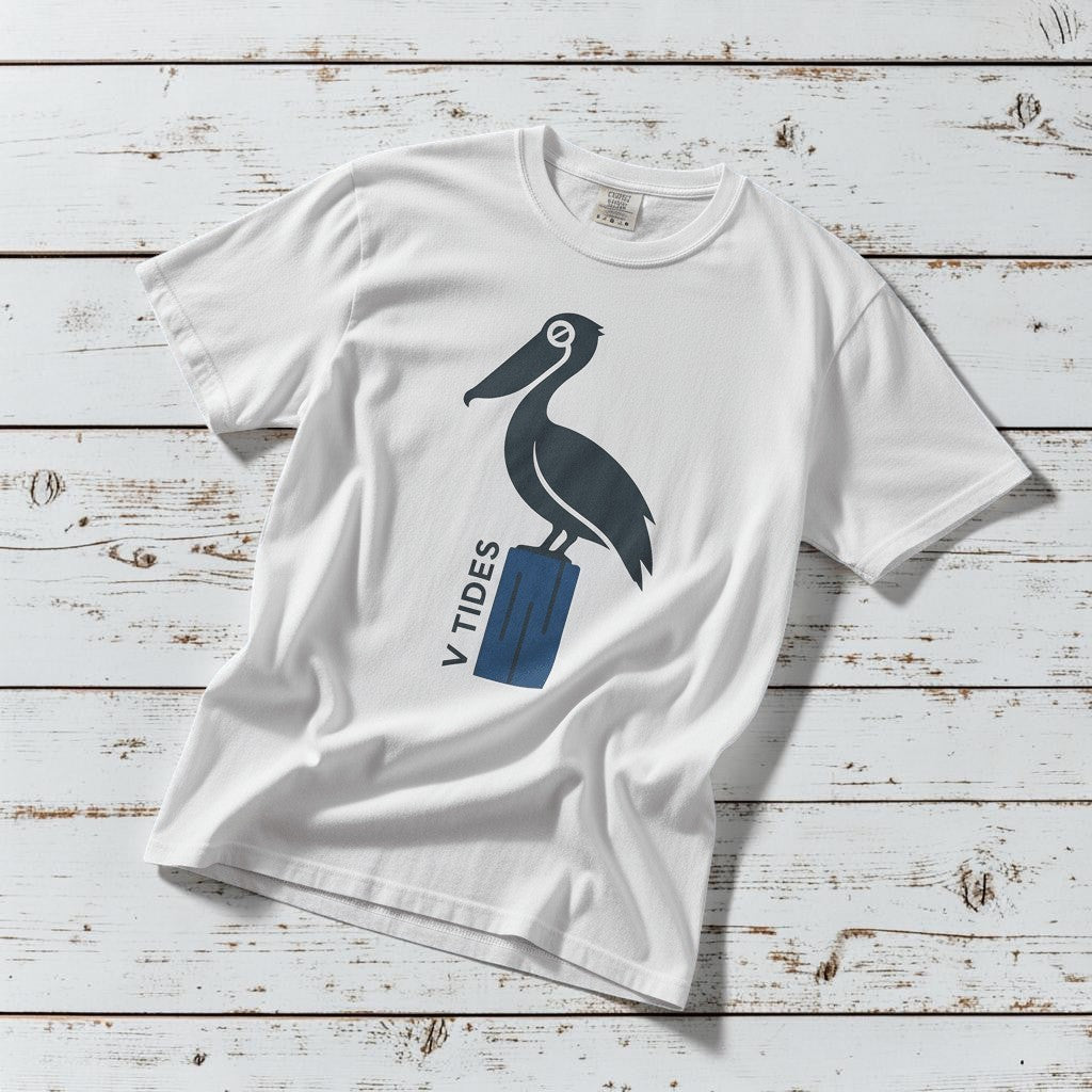 Pelican Dock V Tides coastal graphic t-shirt in White casually tossed on a light sand-colored woven rug, coastal