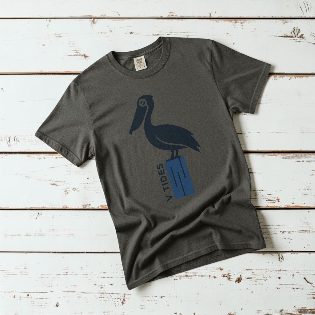 Pelican Dock V Tides coastal graphic t-shirt in Pepper dark charcoal casually tossed on a light sand-colored woven rug