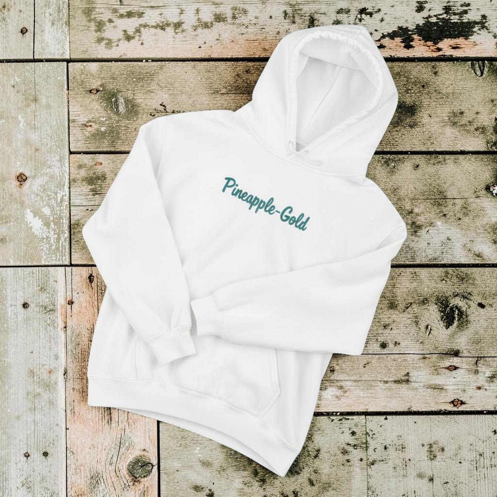 Pineapple-Gold Hoodie in White — front chest graphic, warm sand studio background